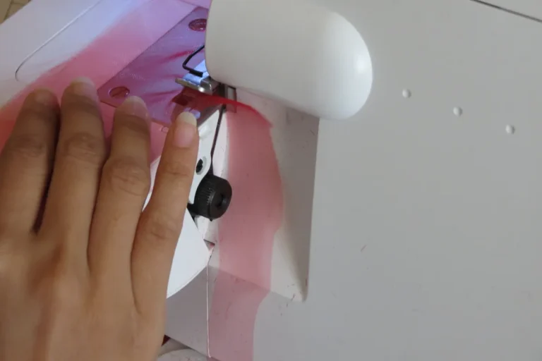 Mains guidant un tissu rose sous le pied presseur d'une surjeteuse blanche